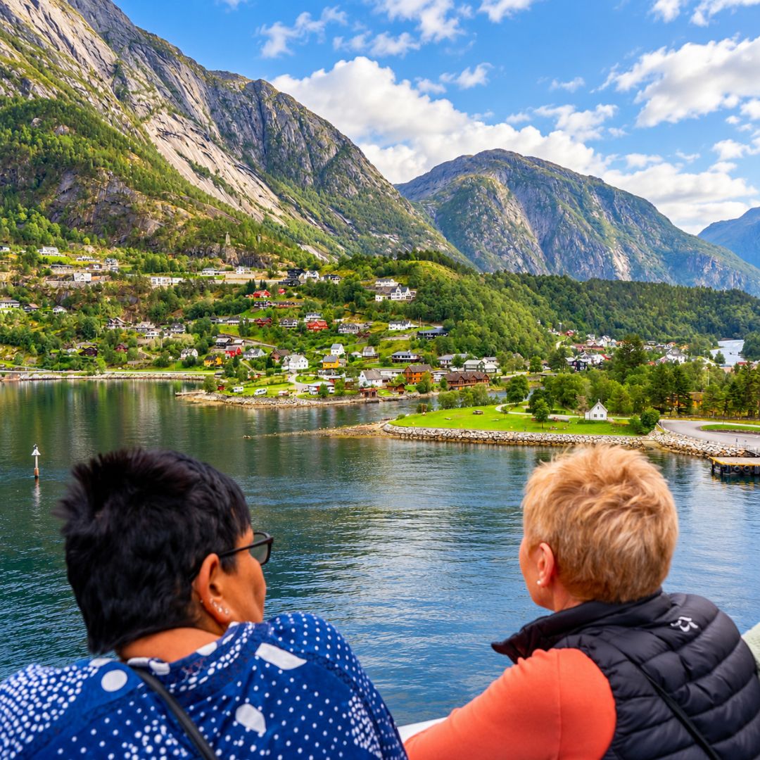 Two passengers enjoying the view of a Norwegian fjord and mountains