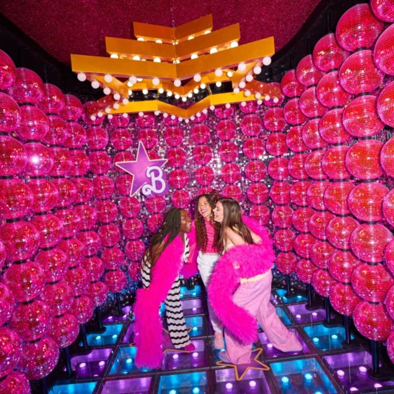 Visitors posing in a dazzling pink Barbie photo setting
