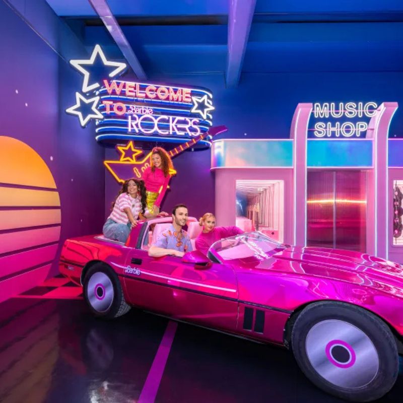 Visitors posing beside Barbie's pink convertible