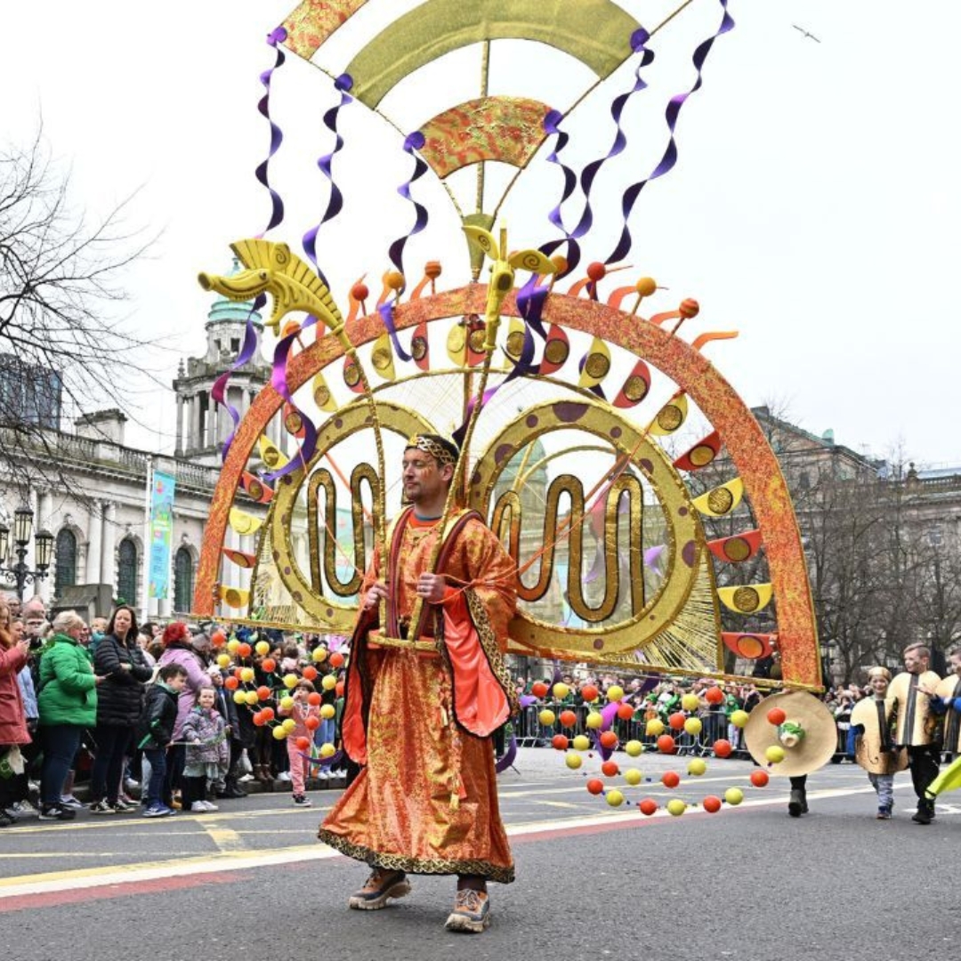 A performer in an elaborate gold and orange costume at Belfast’s St Patrick’s parade