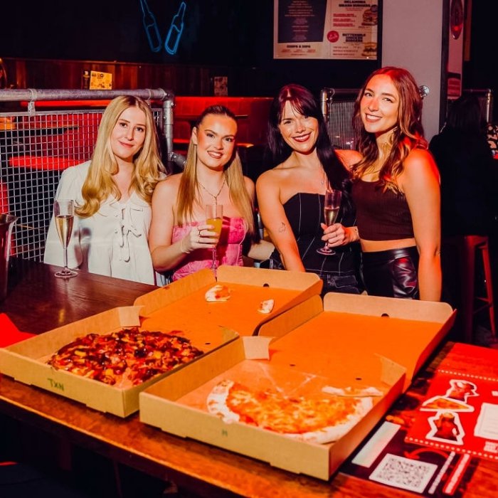 Friends gathered around pizzas at a Coyote Ugly brunch