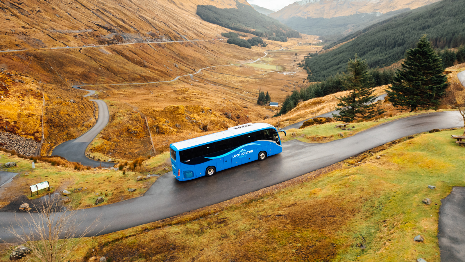 Loch Lomond Travel coach following a winding road through autumn scenery