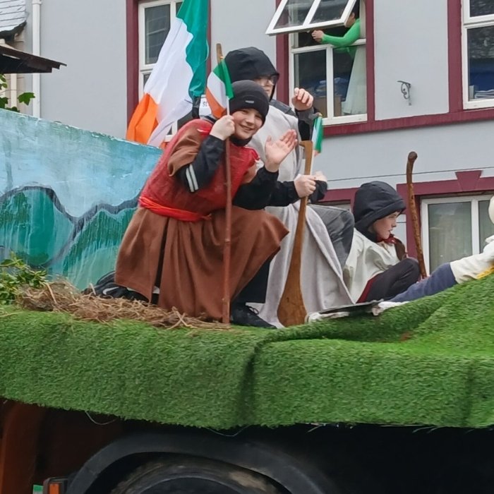 Parade participants waving from a decorated float