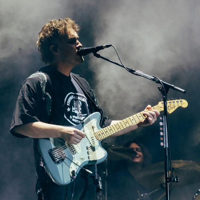 Sam Fender singing and playing guitar on stage